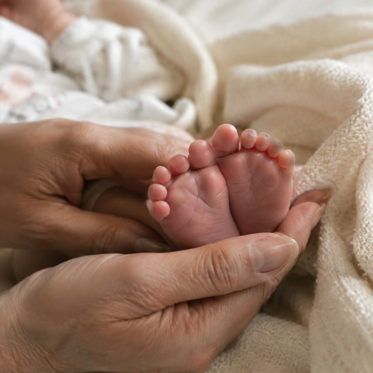 A mother holding her newborn baby's feet